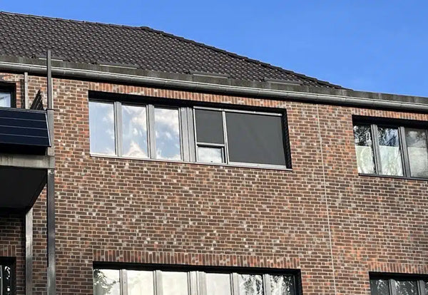 Een rolgordijn op de gevel van een woongebouw beschermt de ramen tegen direct zonlicht.